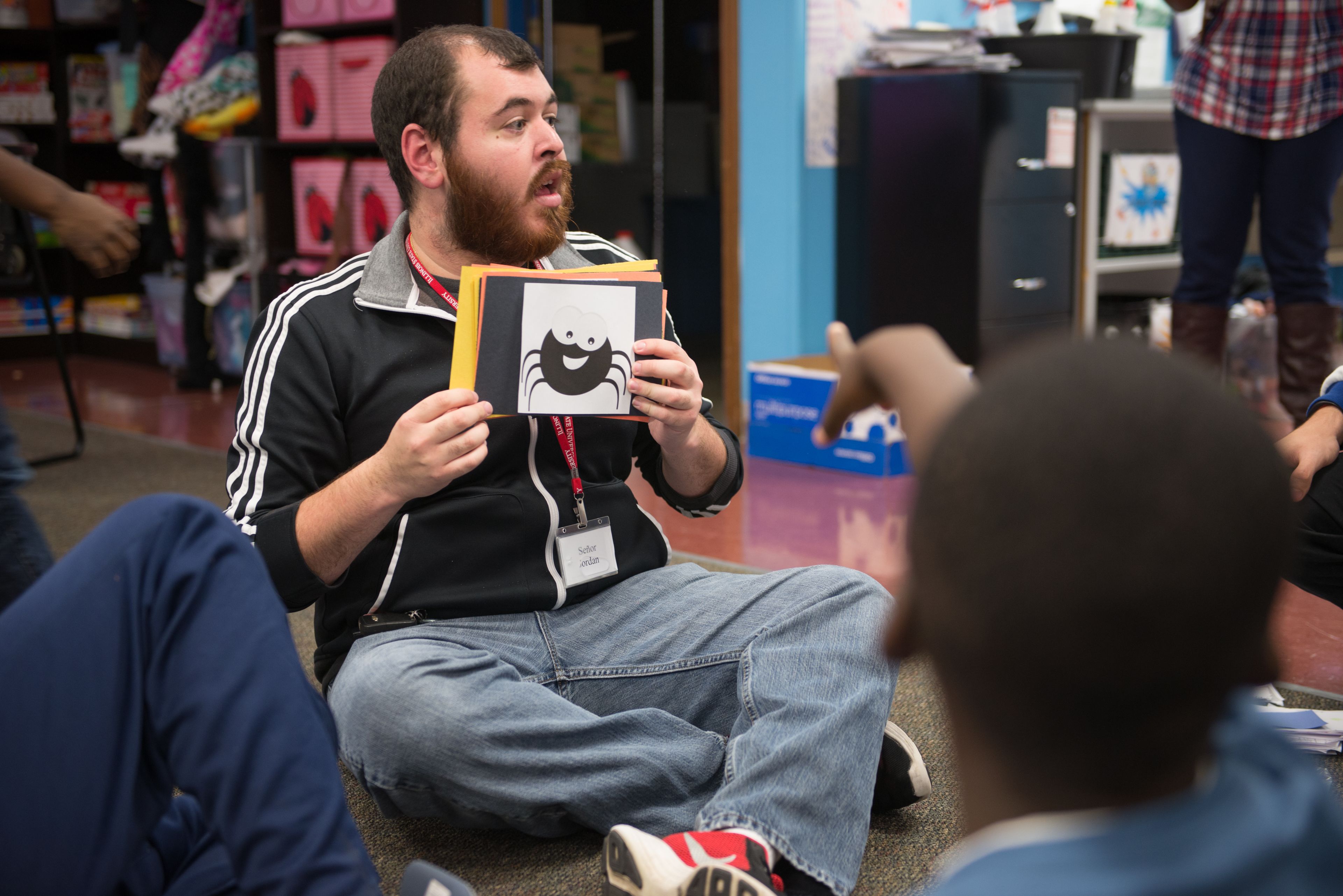 student holding up a picture in front of children