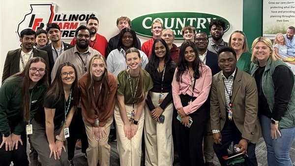 students posed in front of the Country financial sign and Illinois Farm sign