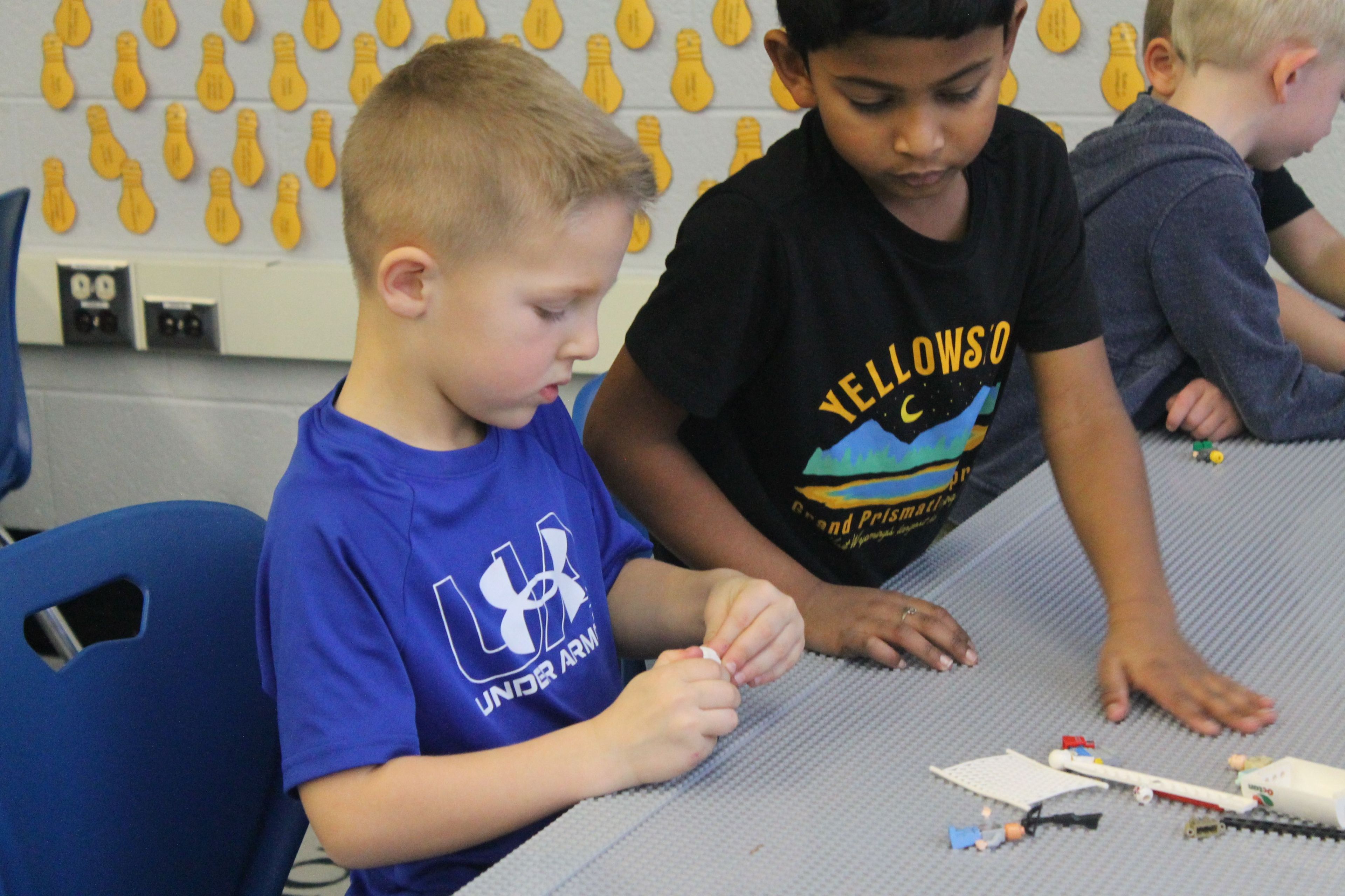 Crew and Arav are working with lego pieces on a counter.