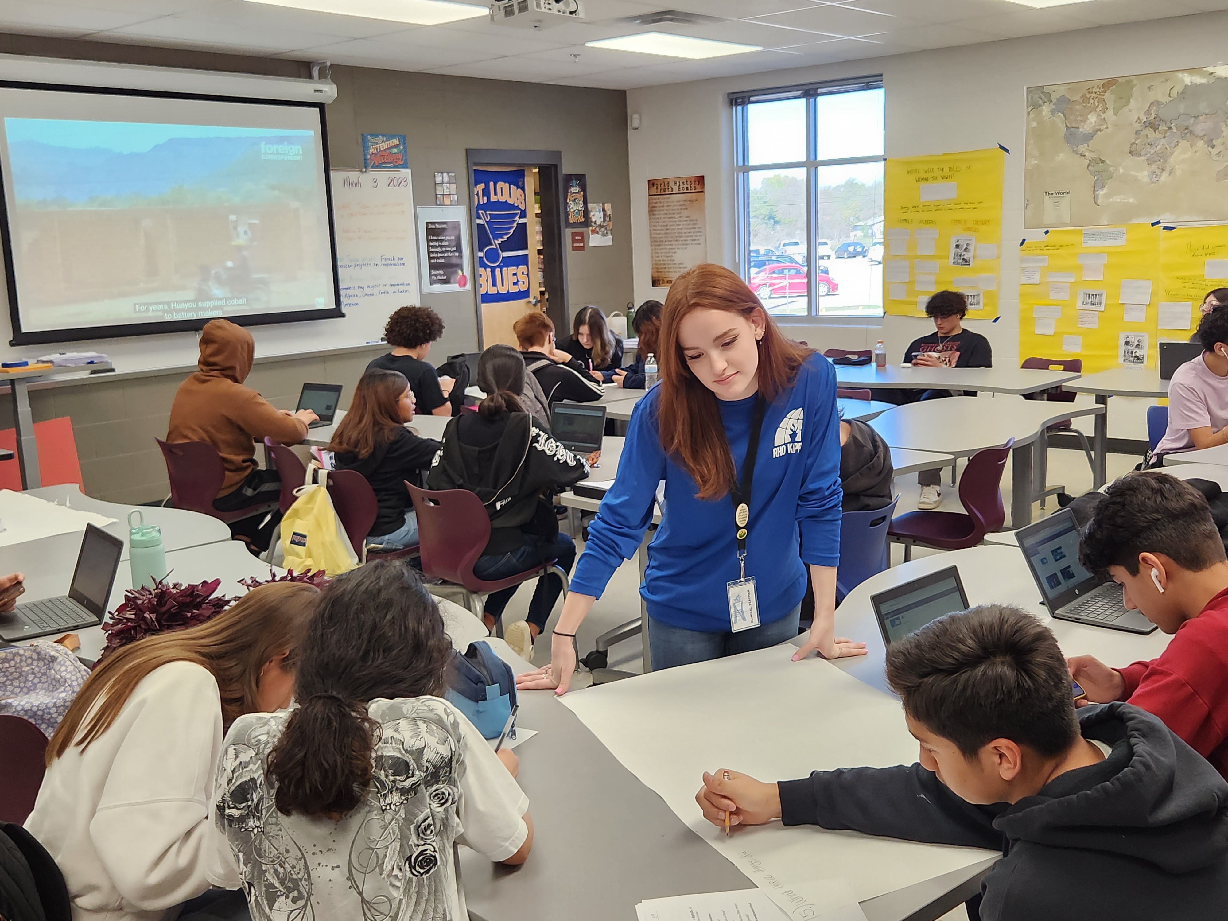 Isabella is speaking with students at their desks.