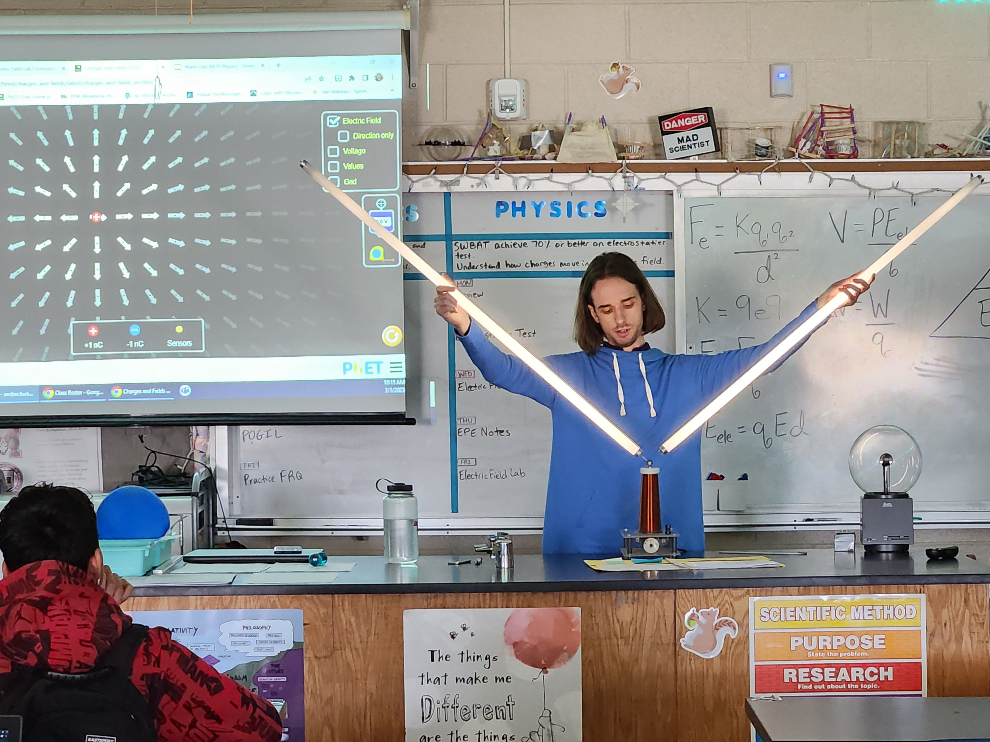 Joseph is holding two fluorescent bulbs for his experiment.