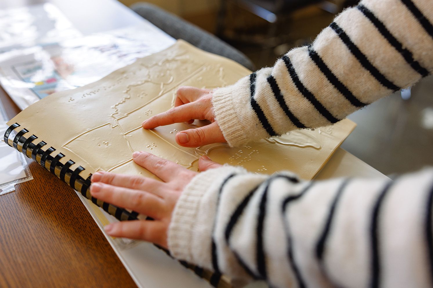 A student's hands are touching the page of a tactile map.